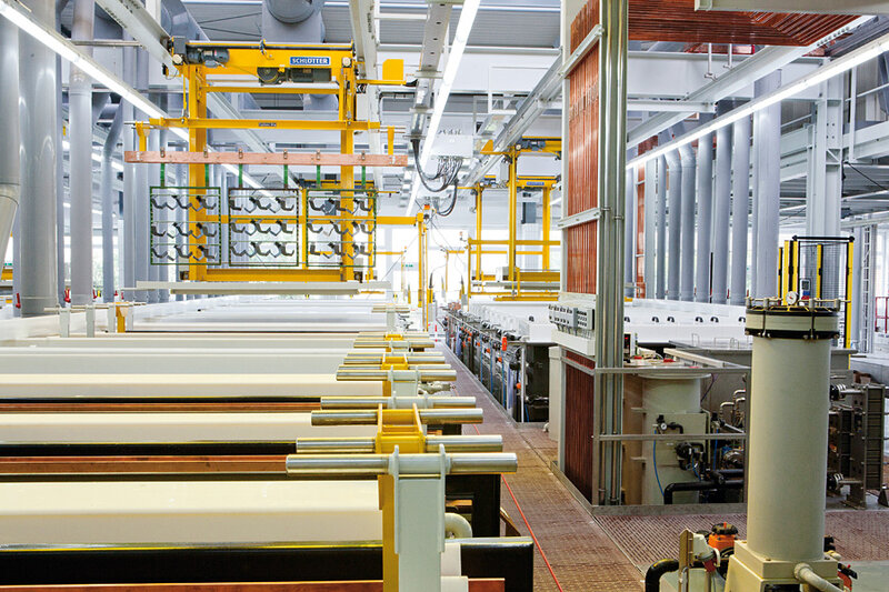 Moderne Industrieanlage mit weißen großen Behältern, gelben Hebewerkzeugen und Rohrleitungen in einer gut beleuchteten Fabrikumgebung