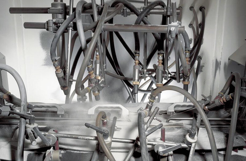 Industrieroboteranlage mit mehreren schwarzen Schläuchen, Ventilen und dampfendem Nebel auf einer Metallfläche