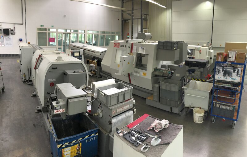 Industrielle Fertigungshalle mit CNC-Drehmaschinen und verschiedenen Lagerbehältern und Werkzeugen