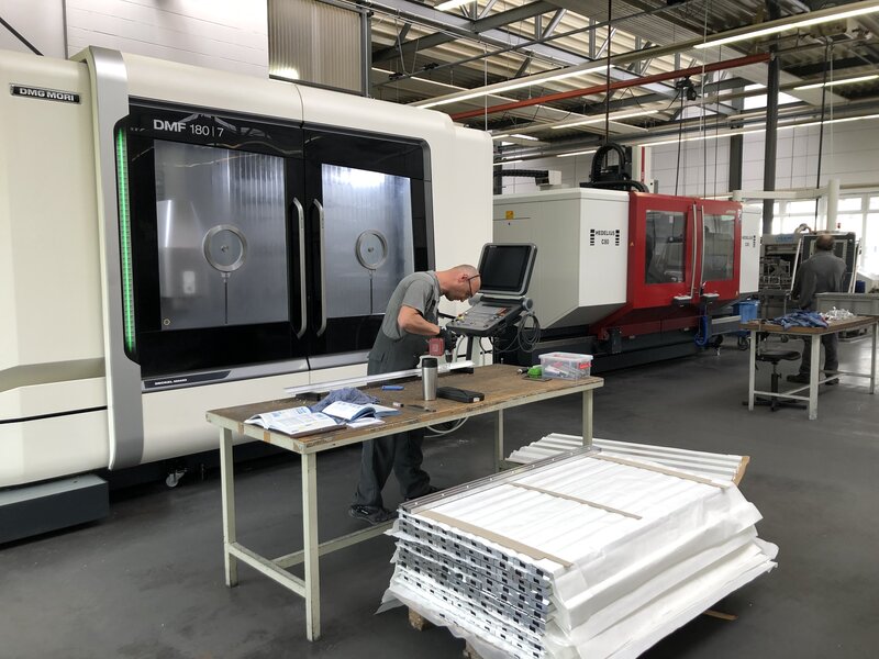 Arbeiter bedient CNC-Steuerung vor einer großen DMG MORI CNC-Maschine in einer Werkhalle