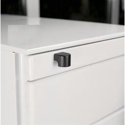Close-up of a white drawer corner with a black, rounded corner handle attached.