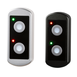 Two TG7 push-button housings: one natural aluminum color and one black anodized, each with two illuminated circular push-buttons and red and green status LEDs